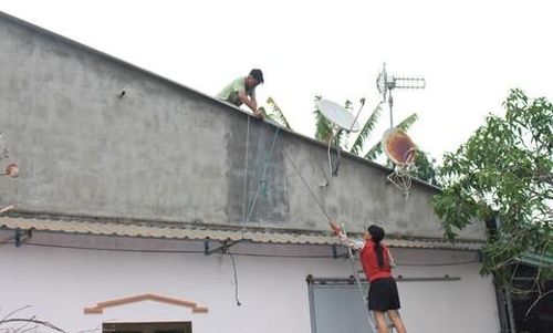 Người dân đang dùng dây thừng cột chắt mái tôn trên nhà.
