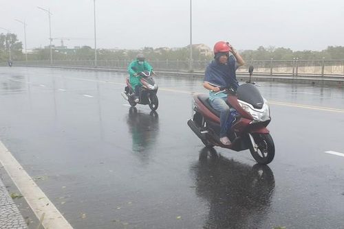 Người dân gặp khó khăn do gió lớn khi di chuyển qua cầu Phú Xuân.
