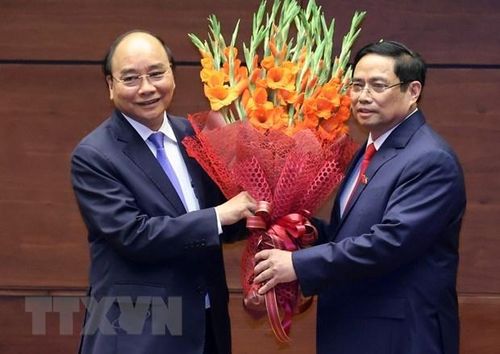 Thủ tướng Phạm Minh Chính tặng hoa Chủ tịch nước Nguyễn Xuân Phúc, Thủ tướng Chính phủ nhiệm kỳ 2016-2021. (Ảnh: Thống Nhất/TTXVN)