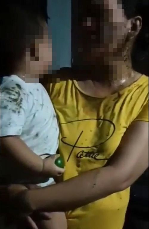 Hai mẹ con mặt mũi đầy phân. Ảnh cắt từ clip