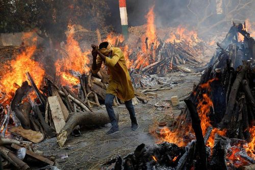 Một người đàn ông chạy qua dàn hỏa thiêu bệnh nhân COVID-19. Ảnh: Reuters
