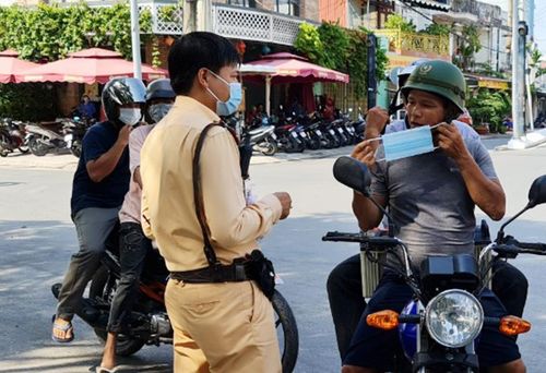 CSGT tại Phú Quốc đã dừng xe người đi đường để phát khẩu trang, khuyến cáo mọi người tuân thủ các quy định phòng, chống dịch bệnh Covid-19. Ảnh: Việt Tường.