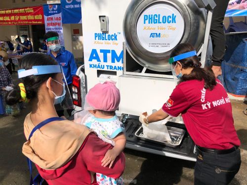 Một phụ nữ bế con đến nhận gạo ở ATM gạo di động