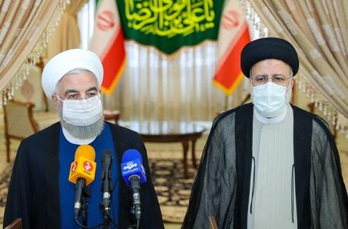 Tổng thống sắp mãn nhiệm Iran Hassan Rouhani (trái) gửi lời chúc mừng Tổng thống đắc cử Ebrahim Raisi (phải) trong cuộc họp báo ở Tehran ngày 19/6/2021. (Ảnh: AFP/TTXVN)
