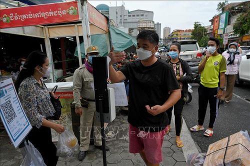 Kiểm tra thân nhiệt phòng lây nhiễm COVID-19 trước khi vào chợ tại Phnom Penh, Campuchia. Ảnh: AFP/TTXVN