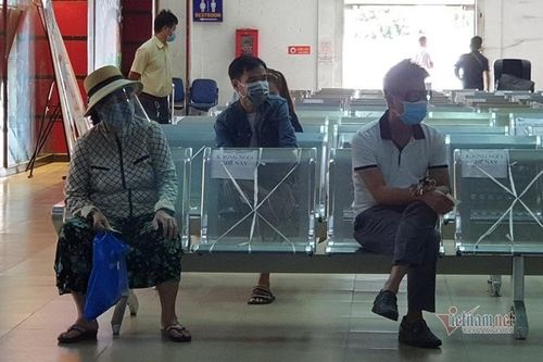 Hành khách ngồi giãn cách chờ đến lượt mua vé 