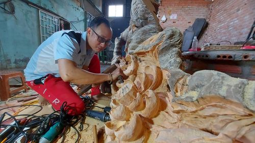 Anh Trần Đức Vinh cặm cụi sáng tạo nghệ thuật từ gỗ lũa. Ảnh: Nguyễn Tú