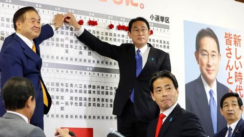 Thủ tướng Kumio Kishida (giữa) gắn hoa lên tên ứng viên trên bảng chiến thắng tại trụ sở LDP ở Tokyo hôm 31/10. Ảnh: Nikkei Asia.