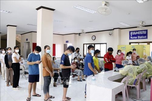 Học sinh từ độ tuổi từ 12-17 tuổi đang chờ quét mã QR để kiểm tra lịch hẹn tại bệnh viện Setthathirath, thủ đô Vientiane, trước khi được phát thẻ vào tiêm vaccine ngừa COVID-19. Ảnh: Phạm Kiên/Pv TTXVN tại Lào