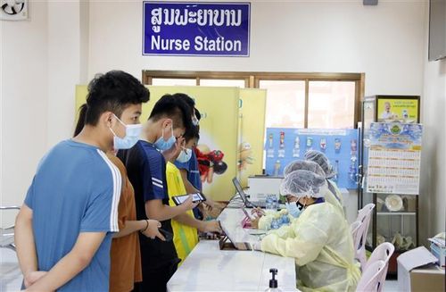 Học sinh độ tuổi từ 12-17 đang chờ quét mã QR để kiểm tra lịch hẹn tại bệnh viện Setthathirath, thủ đô Vientiane, trước khi được phát thẻ vào tiêm vaccine ngừa COVID-19. Ảnh: Phạm Kiên/Pv TTXVN tại Lào