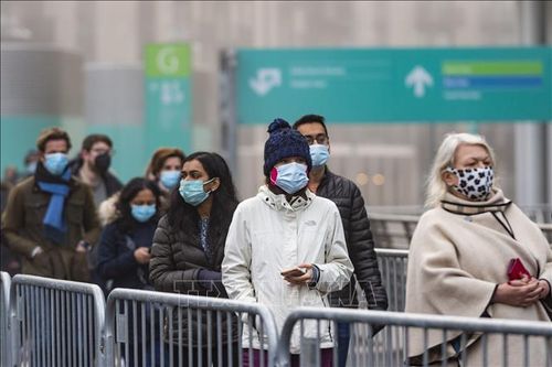 Người dân xếp hàng chờ tiêm vaccine phòng COVID-19 tại London, Anh ngày 19/12/2021. Ảnh: THX/TTXVN