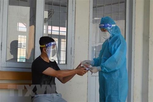 Cán bộ Trạm Y tế kiểm tra sức khỏe và hướng dẫn sử dụng thuốc hỗ trợ điều trị COVID-19 cho đối tượng F0 đang điều trị tại nhà. (Ảnh: Nhựt An/TTXVN)