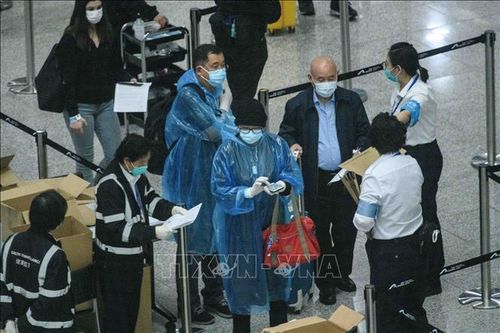 Hành khách đeo khẩu trang phòng lây nhiễm COVID-19 tại sân bay quốc tế ở Hong Kong, Trung Quốc. Ảnh: AFP/TTXVN