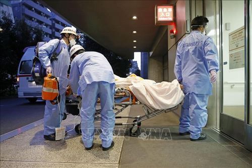 Nhân viên y tế chuyển bệnh nhân COVID-19 tới bệnh viện tại Tokyo, Nhật Bản. Ảnh: Kyodo/TTXVN