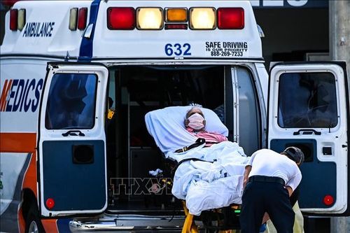 Nhân viên y tế chuyển bệnh nhân nhiễm COVID-19 tới bệnh viện ở Miami, Mỹ. Ảnh: AFP/TTXVN