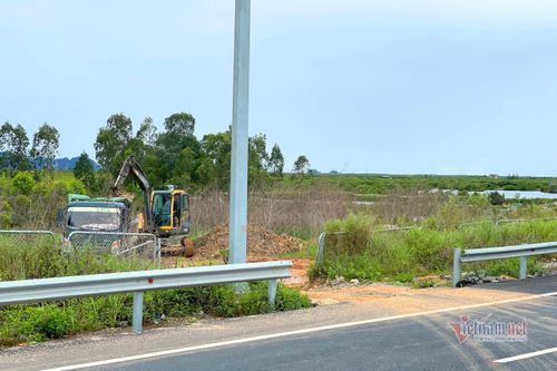 Xe múc đất đưa lên ôtô tải để chạy qua hàng rào, cắt ngang cao tốc.