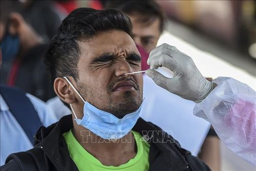 Nhân viên y tế lấy mẫu xét nghiệm COVID-19 cho người dân tại Mumbai, Ấn Độ. Ảnh: AFP/TTXVN