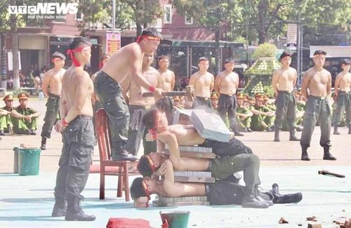 3 chiến sĩ Cảnh sát cơ động nằm chồng lên nhau qua lớp chông sắt để thực hiện màn biểu diễn công phá đá trên bụng.