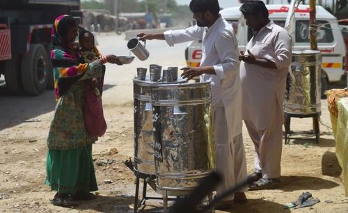 Các tình nguyện viên phân phát nước cho một người phụ nữ và trẻ em. Ảnh: Rizwan Tabassum / AFP / Getty Images.