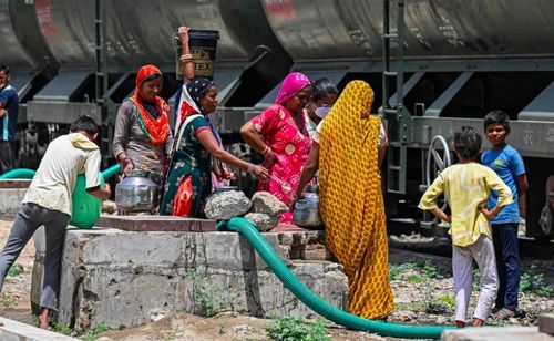 Những người phụ nữ đổ đầy nước vào bình do một đoàn tàu chở nước ở bang Rajasthan - vùng sa mạc của Ấn Độ. Ảnh: Prakash Singh / AFP / Getty Images.