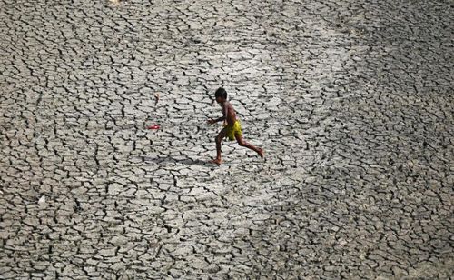 Một cậu bé chạy ngang qua đáy sông khô cằn tại Yamuna. Ảnh: Sajjad Hussain / AFP / Getty Images.