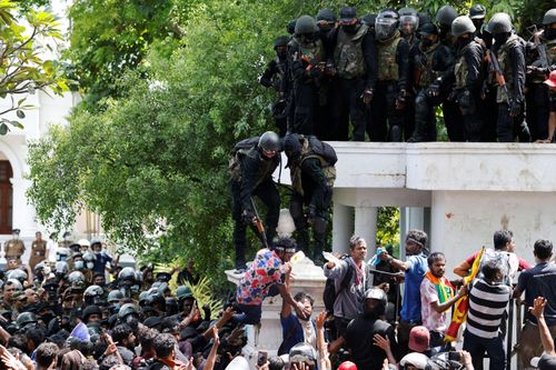  Nhân viên an ninh đẩy một người đàn ông khi đám đông biểu tình bên ngoài văn phòng Thủ tướng Ranil Wickremesinghe ngày 13/7. Ảnh: Reuters. 