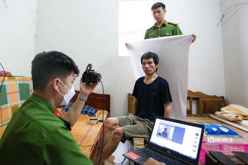 Đại úy Hoàng Mạnh Cường - Phó trưởng Công an xã Tân Hội (đang giơ phông trắng) phối hợp cùng Thượng úy Doãn Văn Thắng làm thủ tục cấp căn cước cho công dân tại nhà.