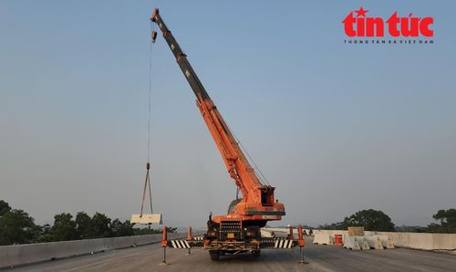 Công nhân cẩu dải phân cách cứng đúc tại chỗ chuẩn bị lắp đặt cố định, phân làn đường trên mặt cầu núi Đọ.