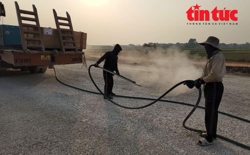 Công nhân gói thấu XL13 vệ sinh mặt đường cấp phối đá dăm trước khi thảm bê tông nhựa nóng.