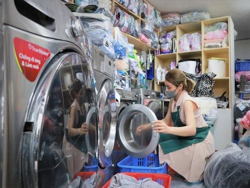 Các cửa tiệm giặt là thường phải hoạt động liên tục vì nhu cầu giặt tăng hơn khi trời nồm. Ảnh Nguyễn Thúy