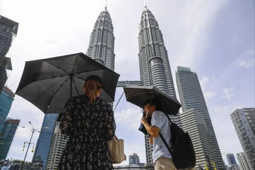 Người dân mang theo dù khi trời nắng nóng bất thường ở Kuala Lumpur. Ảnh: EPA-EFE.