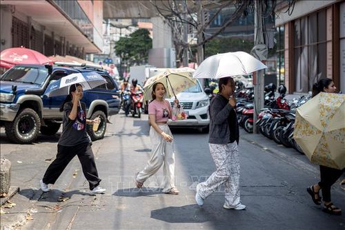 Người dân dùng ô che nắng khi di chuyển trên phố ở Bangkok, Thái Lan ngày 20/4. Ảnh: AFP/TTXVN