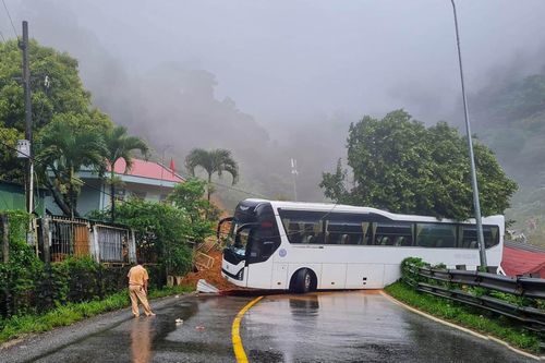Một xe chở khách du lịch bị đất đá sạt lở chặn lối đi.