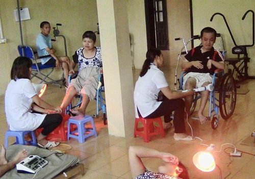 Cán bộ Trung tâm Chăm sóc nuôi dưỡng và Điều trị nạn nhân bị nhiễm chất độc da cam/dioxin Hà Nội giúp các bệnh nhân phục hồi chức năng. Ảnh: TTXVN
