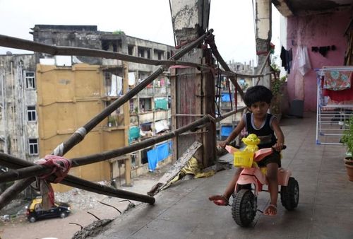 Trẻ em chơi bên ngoài căn hộ của mình dọc theo các hành lang với lan can rỉ sét, gãy được giữ bằng vải vụn và các thanh thép gia cố.