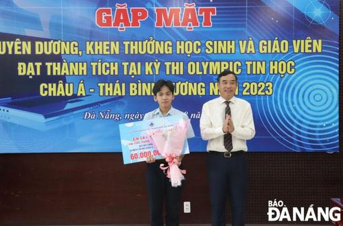 Chủ tịch UBND thành phố Lê Trung Chinh (phải) tặng Bằng khen và tiền thưởng cho học sinh Lê Ngọc Bảo Châu. Ảnh: NGỌC HÀ