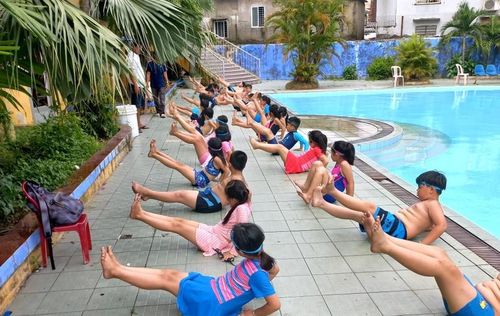 Học sinh tập các bài tập khởi động trước khi bơi.