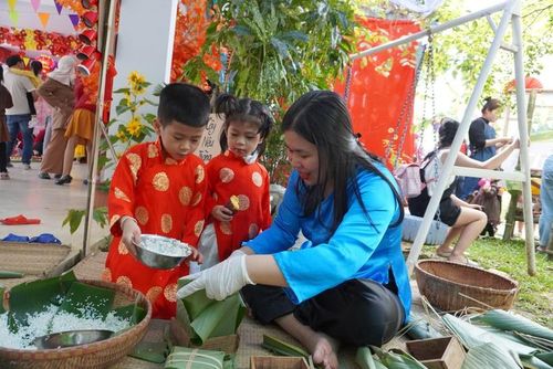 Trẻ mầm non được trải nghiệm gói bánh chưng.