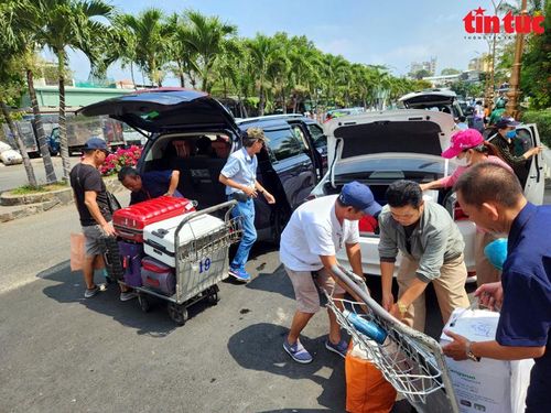Trước cửa sân ga, nhiều người đang chuyển hành lý từ xe ô tô xuống.