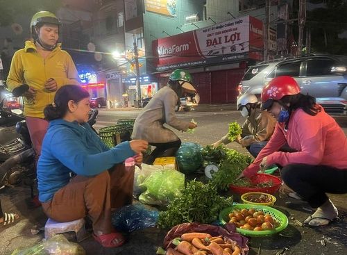 Chị Lai (áo xanh) ngồi nán lại muộn hơn để cố bán cho hết số rau, củ. Ảnh: P.D
