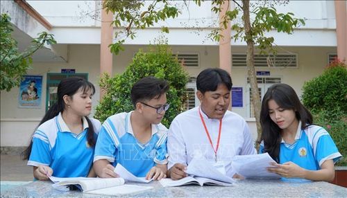 Em Danh Sà Rưm (áo trắng) chia sẻ kinh nghiệm làm bài tập cùng các bạn. Ảnh: Văn Sĩ/TTXVN