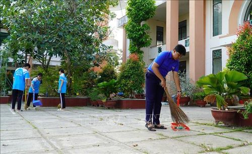 Em Danh Sà Rưm cùng các bạn làm vệ sinh sân trường. Ảnh: Văn Sĩ/TTXVN