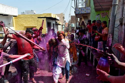Người dân phun nước màu lên du khách trên một con đường nhỏ trong dịp Lễ hội Holi ở thị trấn Nandgaon, Uttar Pradesh, Ấn Độ. (Ảnh: Reuters)