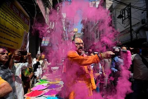 Một người phun bột màu khi mọi người mừng lễ Holi ở Jammu, phía bắc Ấn Độ.