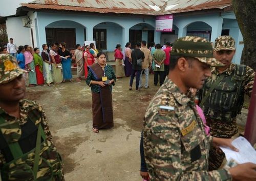 Trong giai đoạn đầu của cuộc tổng tuyển cử ở Imphal, Manipur, Ấn Độ, cử tri xếp hàng chờ bỏ phiếu cạnh nhân viên lực lượng an ninh ngoài một trạm bỏ phiếu.