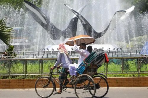  Một chiếc xe kéo đi ngang qua đài phun nước trong đợt nắng nóng đang diễn ra ở Dhaka, Bangladesh. Ảnh: Razu/NurPhoto. 