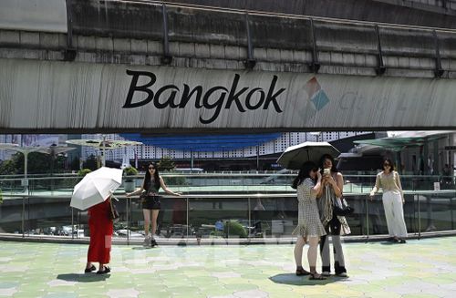 Khách du lịch che ô tránh nắng khi tham quan thủ đô Bangkok, Thái Lan, ngày 1/4/2024. Ảnh: AFP/TTXVN