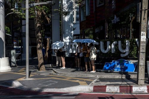  Du khách cầm ô dù, tìm chỗ bóng mát tại Tháo Lan. Ảnh: Bloomberg. 