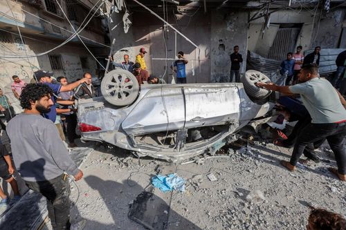 Người dân Palestine cố gắng di chuyển một chiếc ô tô bị hư hại tại địa điểm bị Israel tấn công ở trại tị nạn Nuseirat, trung tâm Dải Gaza, ngày 14/5.