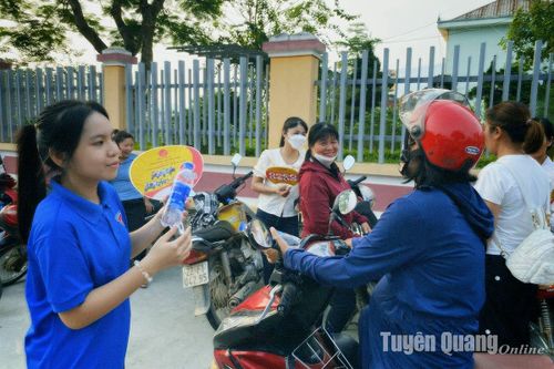 Tình nguyện viên phát nước phục vụ phụ huynh và học sinh tại điểm thi Trường THPT Chiêm Hóa. Ảnh: Bàn Thanh